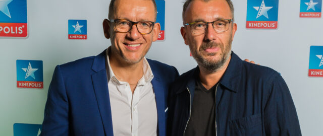 Deux hommes devant un logo Kinepolis.