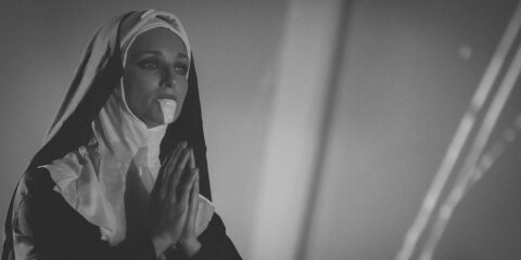 Religieuse en prière portant une robe noire.