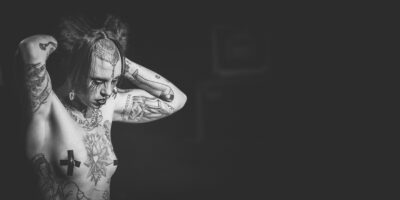 Personne tatouée en noir et blanc, bras levés.