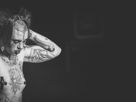 Personne tatouée en noir et blanc, bras levés.