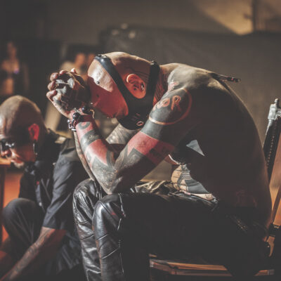 Deux hommes tatoués assis, ambiance mystérieuse.