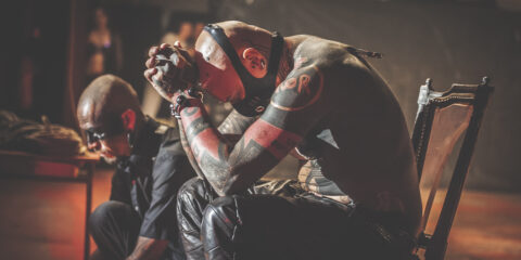 Deux hommes tatoués assis, ambiance mystérieuse.
