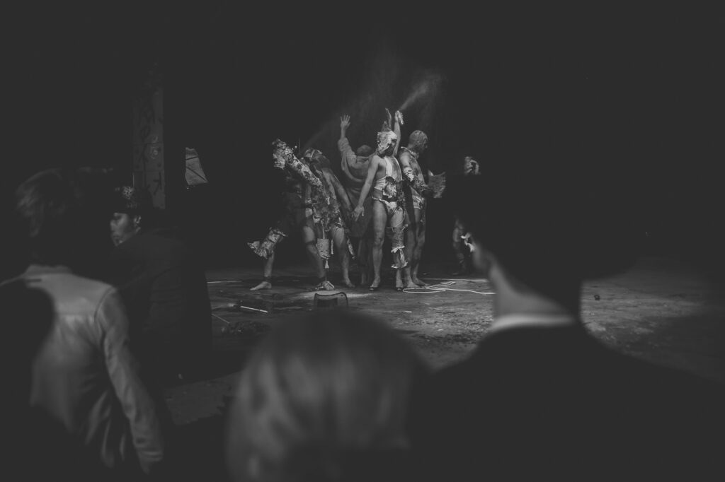 Performance artistique en noir et blanc, public observant.
