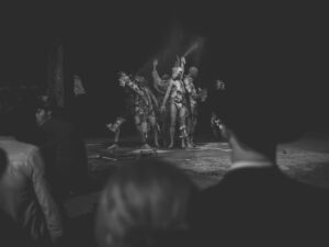 Performance artistique en noir et blanc, public observant.