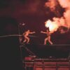 Équilibriste sur fil avec flamme spectaculaire.