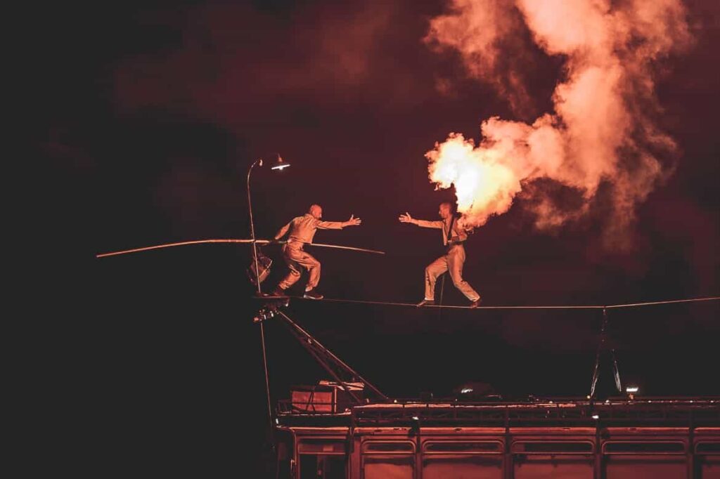Équilibriste sur fil avec flamme spectaculaire.