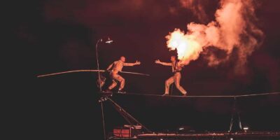 Équilibriste sur fil avec flamme spectaculaire.