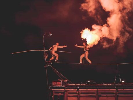 Équilibriste sur fil avec flamme spectaculaire.