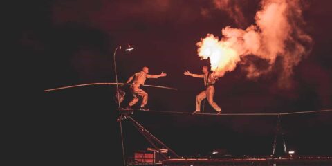 Équilibriste sur fil avec flamme spectaculaire.