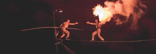 Équilibriste sur fil avec flamme spectaculaire.