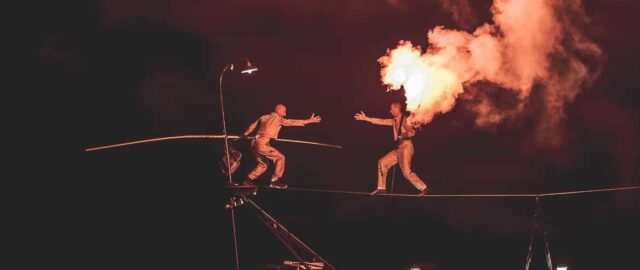 Équilibriste sur fil avec flamme spectaculaire.