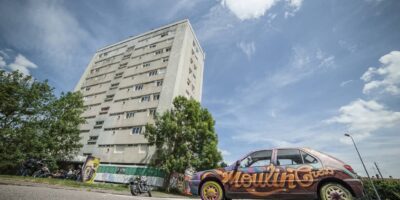 Immeuble et voiture graffée sous ciel bleu.