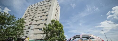 Immeuble et voiture graffée sous ciel bleu.