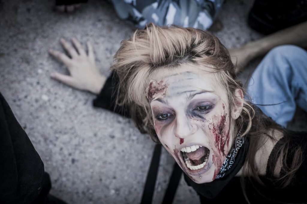 Personne maquillée en zombie effrayée au sol.