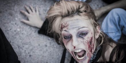 Personne maquillée en zombie effrayée au sol.