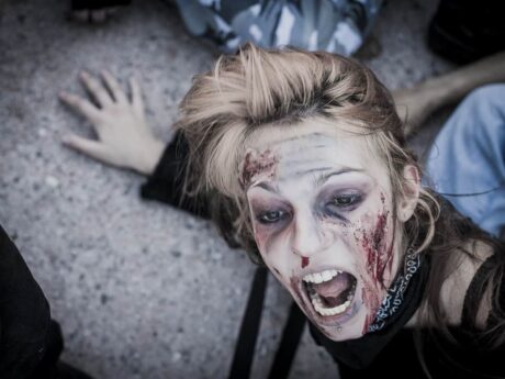 Personne maquillée en zombie effrayée au sol.
