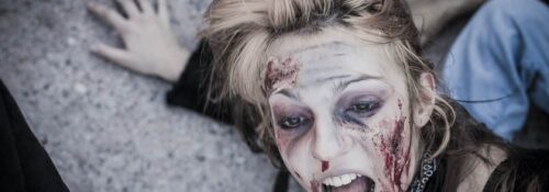 Personne maquillée en zombie effrayée au sol.