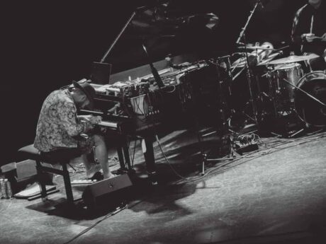 Musicien jouant du piano sur scène avec batterie.