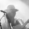 Chanteuse avec guitare sur scène, noir et blanc.