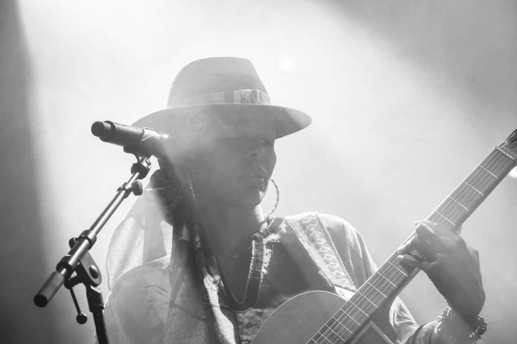 Chanteuse avec guitare sur scène, noir et blanc.