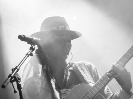 Chanteuse avec guitare sur scène, noir et blanc.