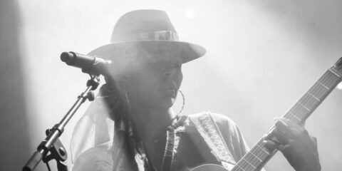 Chanteuse avec guitare sur scène, noir et blanc.