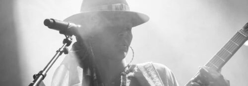 Chanteuse avec guitare sur scène, noir et blanc.