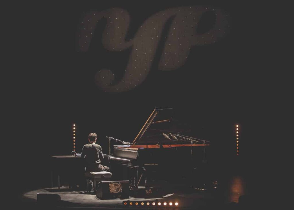 Pianiste en spectacle avec éclairage intense.