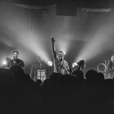 Groupe de musique en concert sur scène éclairée.