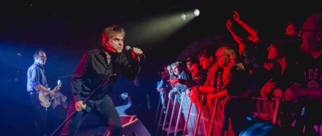 Chanteur sur scène avec la foule enthousiaste.