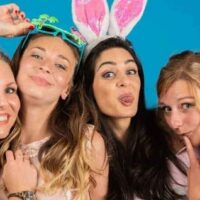 Quatre femmes souriantes avec accessoires amusants.