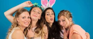 Quatre femmes souriantes avec accessoires amusants.