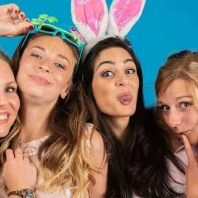 Quatre femmes souriantes avec accessoires amusants.