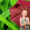 Fille avec parapluie rose, fond verdoyant.