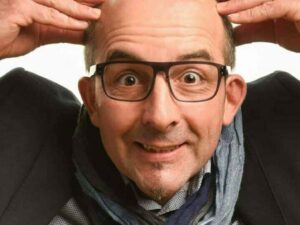 Homme chauve souriant touchant sa tête.