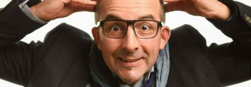 Homme chauve souriant touchant sa tête.