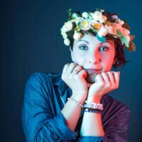 Personne avec couronne de fleurs, pose rêveuse.