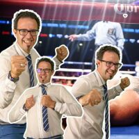 Homme souriant avec poings levés sur fond de ring.