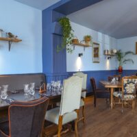 Restaurant élégant avec chaises vintage et décoration murale.