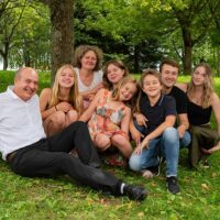 Famille souriante assise sur l'herbe sous les arbres.