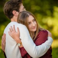 Un couple s'enlace dans un parc verdoyant.