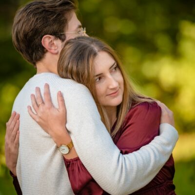 Un couple s'enlace dans un parc verdoyant.