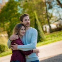 Couple heureux s'enlaçant dans un parc ensoleillé.