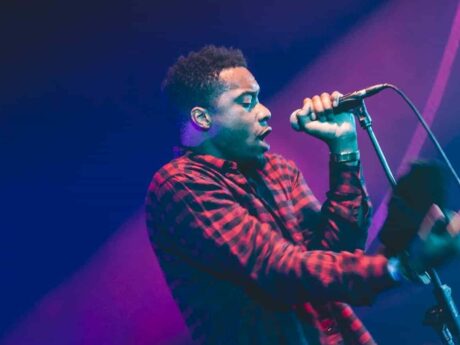 Musicien chante en concert, ambiance lumineuse.