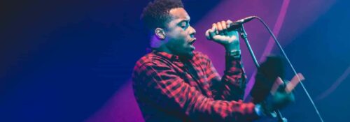 Musicien chante en concert, ambiance lumineuse.