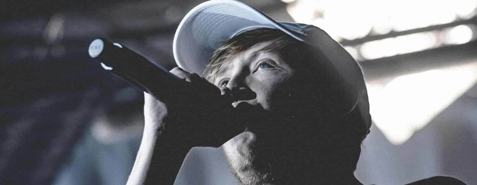 Chanteur avec microphone et casquette sur scène.