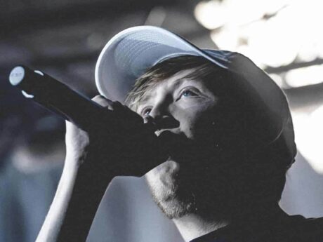 Chanteur avec microphone et casquette sur scène.