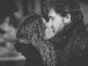 Couple s'embrassant sous la neige.