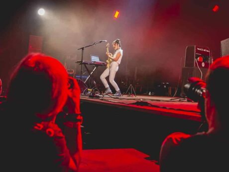 Concert avec musicienne jouant de la guitare sur scène.