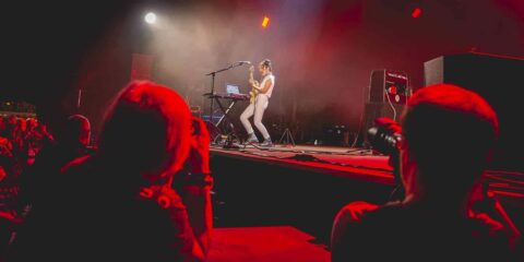 Concert avec musicienne jouant de la guitare sur scène.